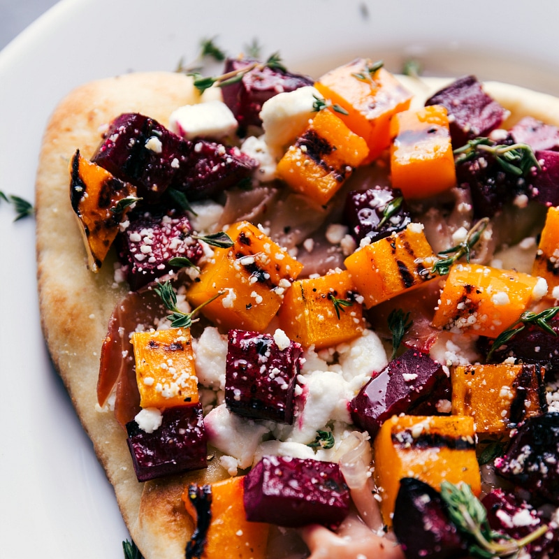 This Beet and Goat Cheese Flatbread makes for a show-stopping, flavorful holiday appetizer. These flatbreads are cooked on the grill! Recipe via chelseasmessyapron #pizza #healthy #quick #easy #simple #fall #grilled #dinner #butternutsquash #thyme #beet #goatcheese #flatbread Up close overhead image of the pizza