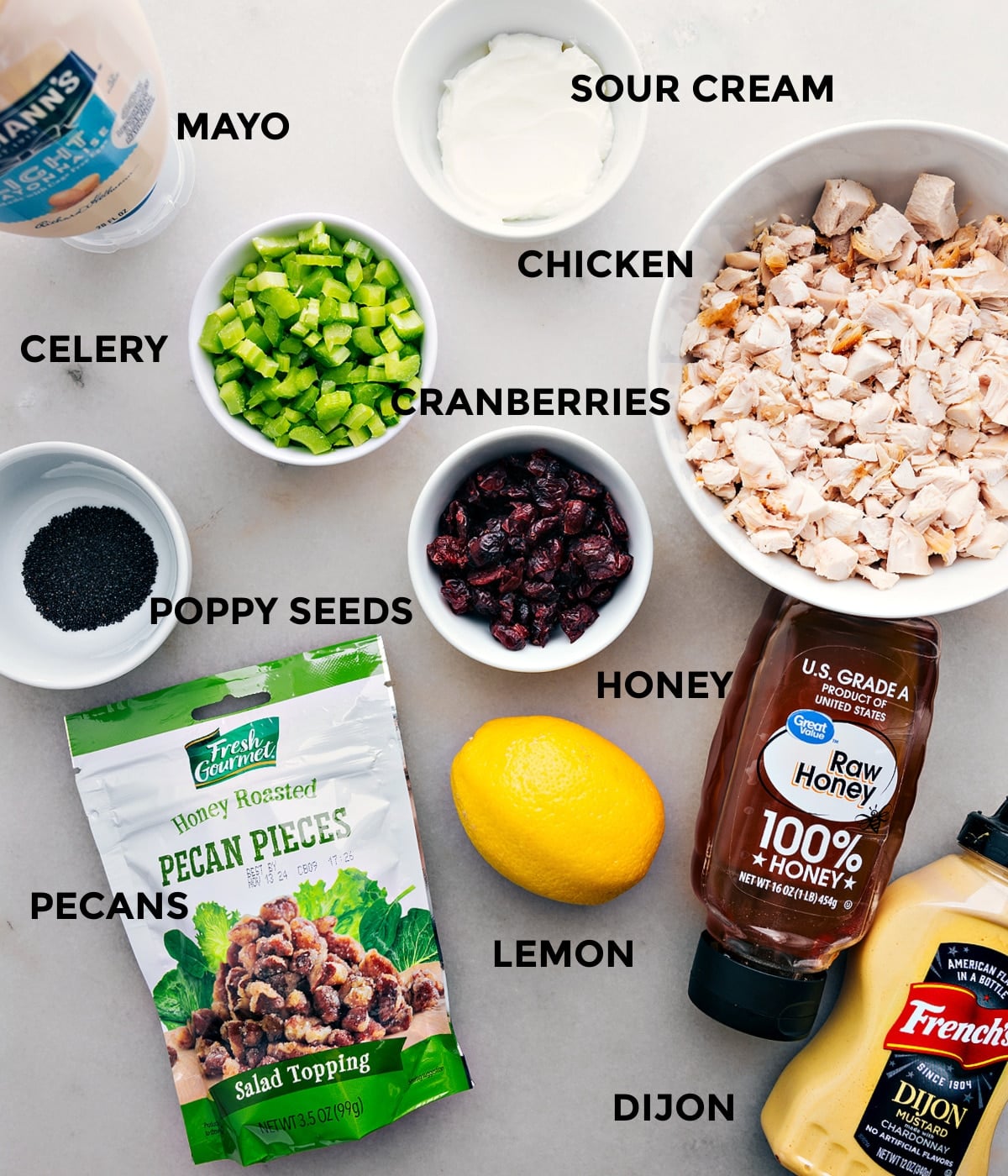 Ingredients In Chicken Salad Recipe All the ingredients in this recipe including meat, sour cream, mayo, celery, cranberries, poppy seeds, lemon, dijon, pecans, and honey prepped out for easy assembly.