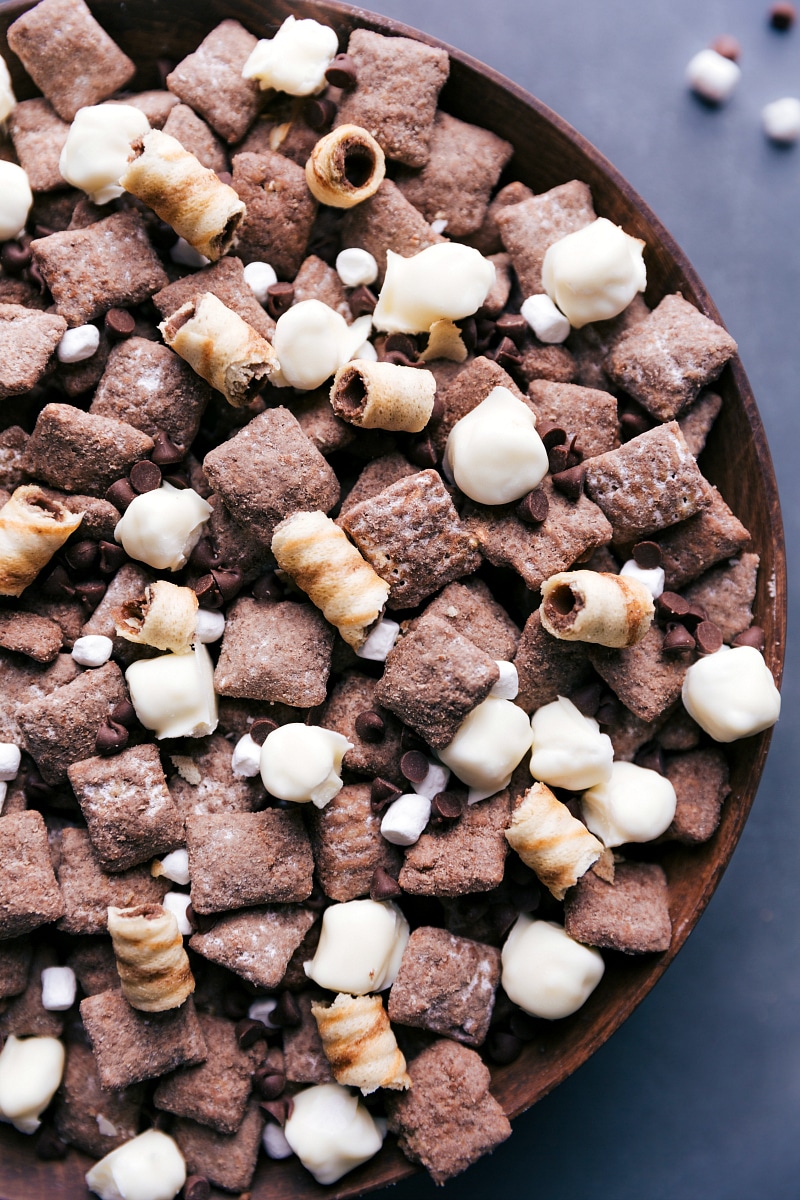 The best ever Hot Chocolate Snack Mix is inspired by our favorite chilly weather beverage -- hot chocolate! Chocolate Chex® cereal is coated in melted chocolate and tossed with a hot cocoa powdered sugar blend. Add in some white chocolate-covered marshmallows and chocolate chips for an unforgettable snack mix! Recipe via ChelseasMessyApron #marshmallows #cozy #christmas #holidays #minimarshmallows #hotchocolate #snack #mix View of the finished Hot Chocolate Snack Mix.