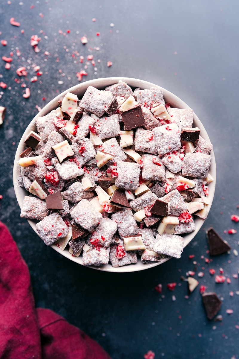 A large bowl filled with peppermint bark muddy buddies, coated in powdered sugar and crushed peppermint.