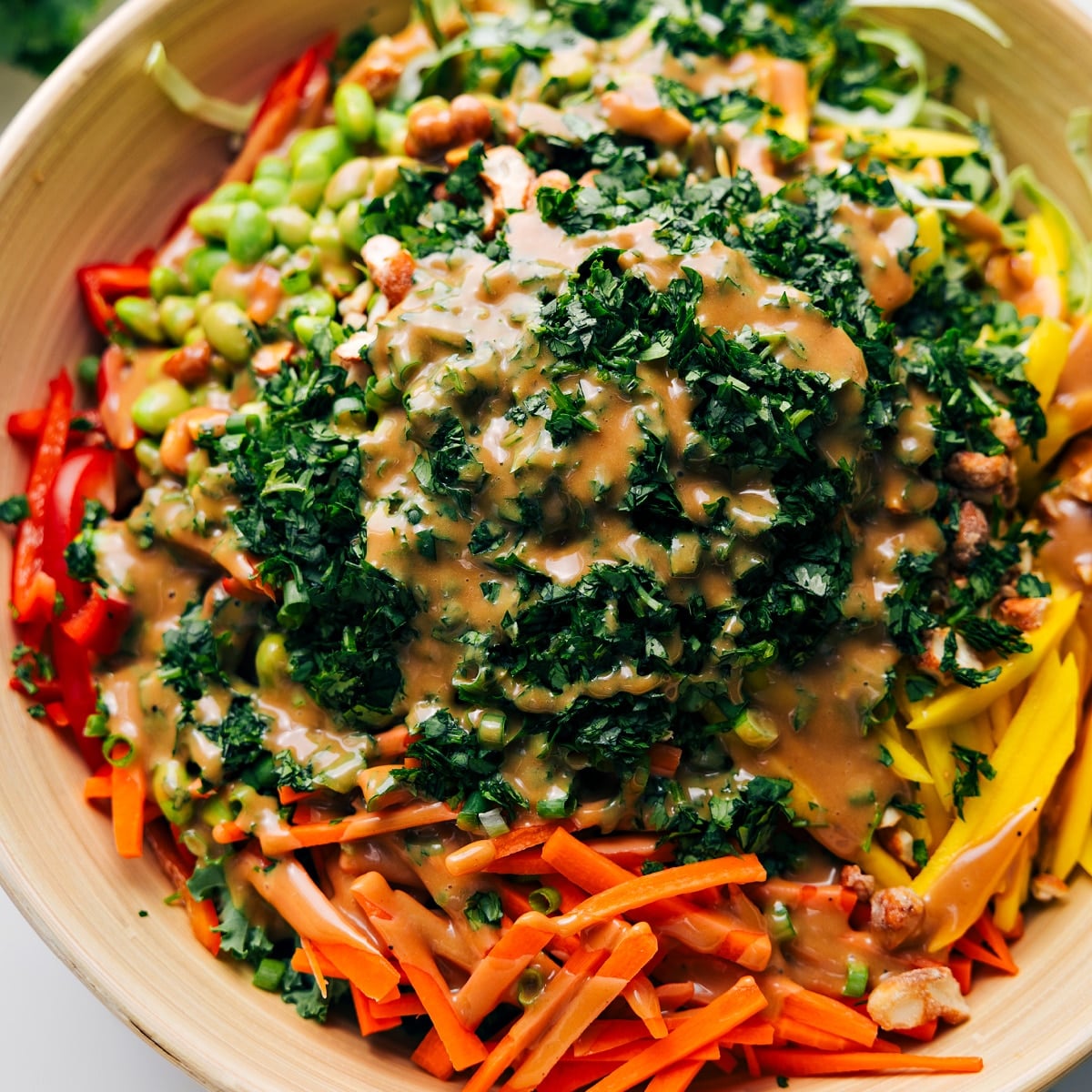 How To Make This This Quinoa Salad Thai Quinoa Salad in a large bowl with the ingredients layered and dressing drizzled over the top before tossing.