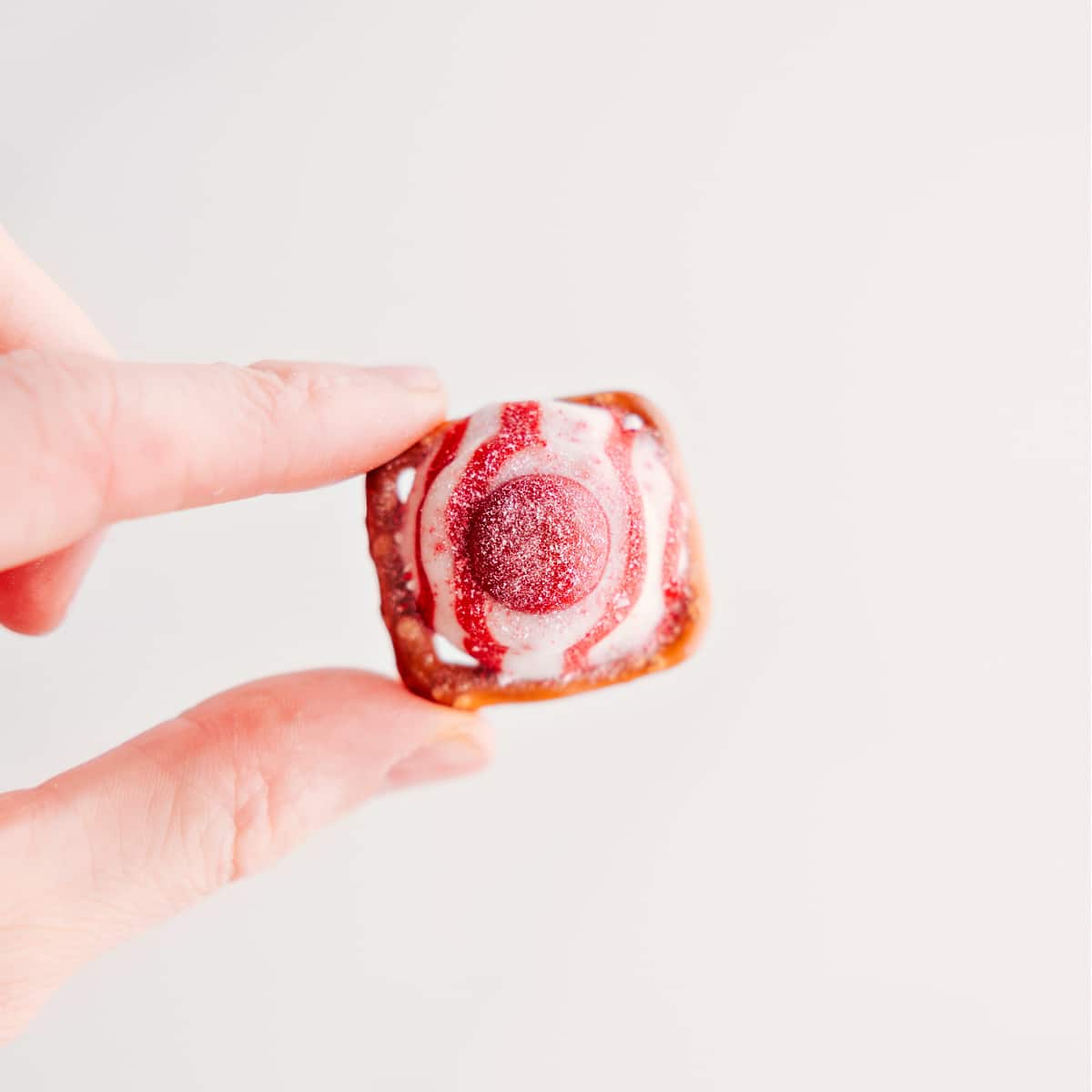 Super Simple Peppermint Bark Pretzels Recipe This three-ingredient holiday treat is held up to showcase its deliciousness.