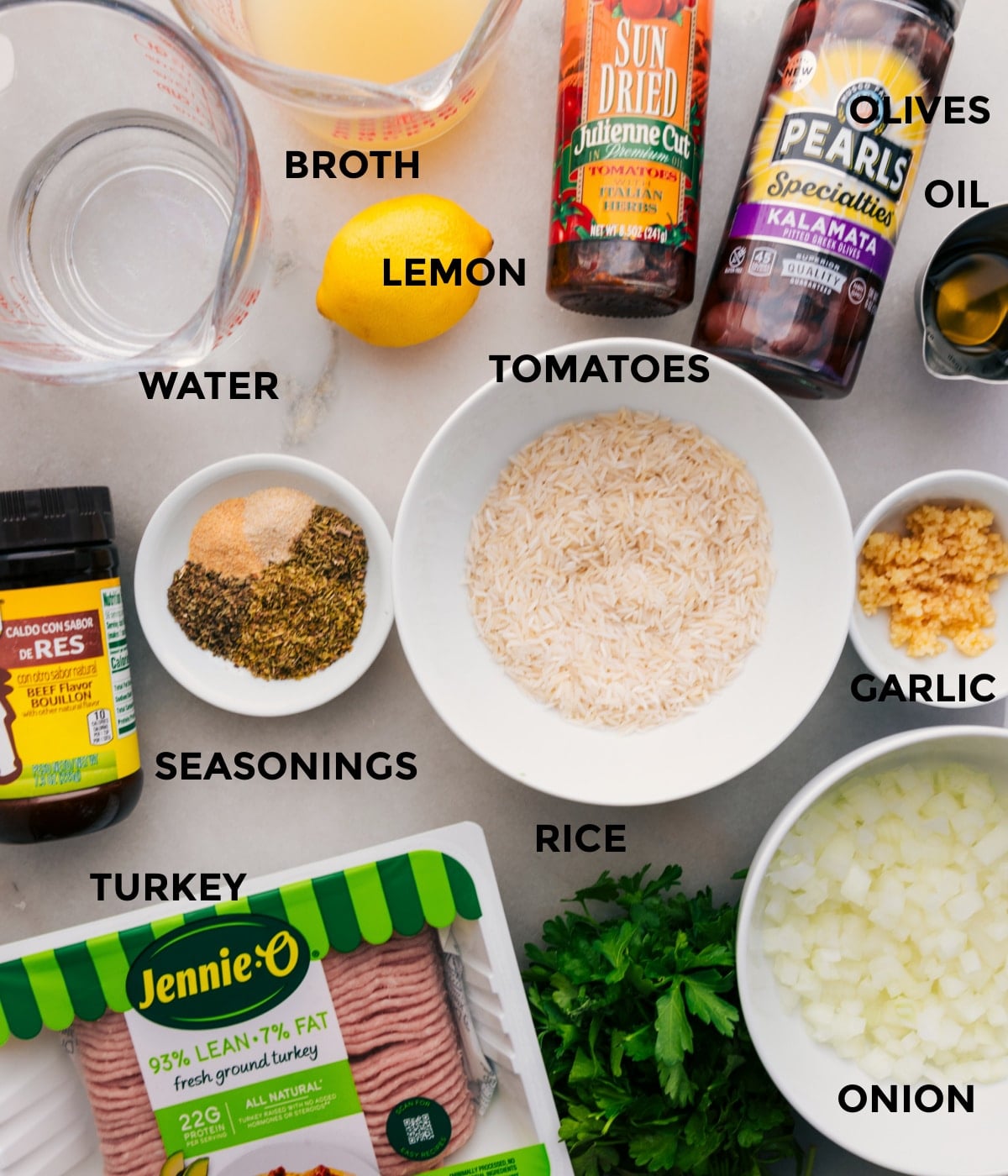 Ingredients In Greek Ground Turkey This recipe includes prepped ingredients like rice, veggies, meat, seasonings, olives, tomatoes, oil, broth, water, and lemons for easy assembly.