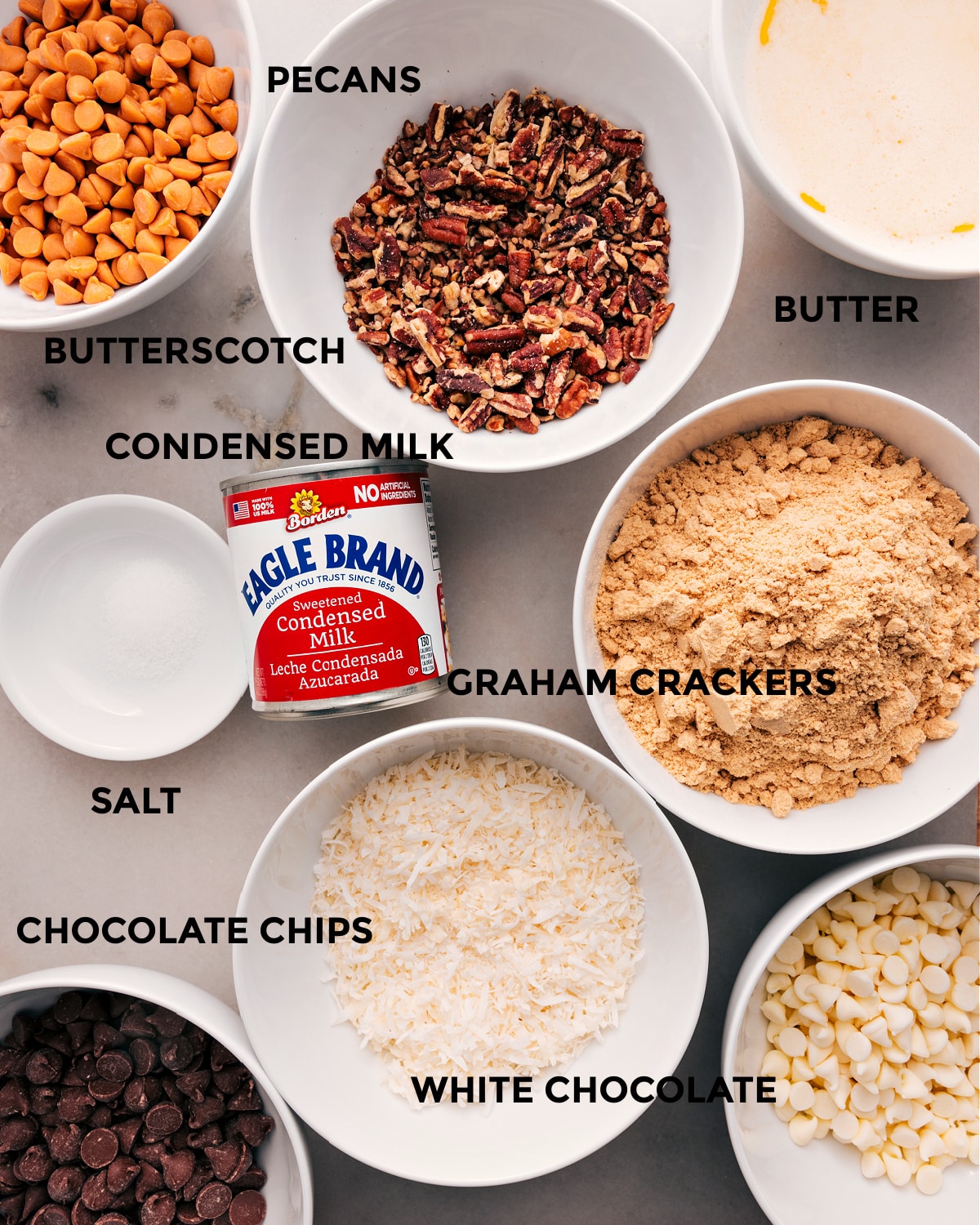 Ingredients In 7-Layer Bars All the ingredients prepped for easy assembly—butter, butterscotch, pecans, condensed milk, graham crackers, salt, coconut, and chocolate chips.