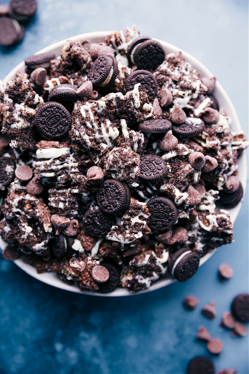 Cookies and Cream Muddy Buddies piled in a bowl, coated in powdered sugar and ready to enjoy.