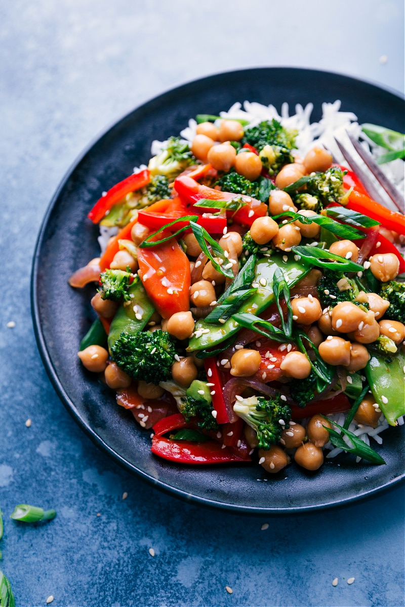 These General Tso Chickpeas make an amazing vegetarian meal with carrots, broccoli, snow peas, a sweet bell pepper, and an array of aromatics. The spicy, tangy sauce that coats these chickpeas and veggies is so quick to whip together and loaded with flavor. Serve these General Tso Chickpeas over rice or cauliflower rice for a low-carb (high-protein) meal. Recipe via chelseasmessyapron #vegan #healthy #clean #veggies #best #quick #easy #simple #broccoli #sesame #generaltso #chickpeas Overhead image of General Tso Chickpeas on a plate, ready to be eaten.
