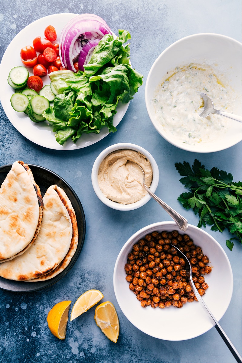 Vegetarian Gyros--they're loaded with robustly-seasoned and perfectly roasted chickpeas, a medley of veggies, and our favorite Tzatziki sauce. This easy, weeknight meal can be ready in about 30 minutes or less if you’ve got an air fryer! #dinner #healthy #whole #whole30 #best #quick #easy #simple #greek #vegetarian #gyros Overhead view of the ingredients laid out on a countertop.