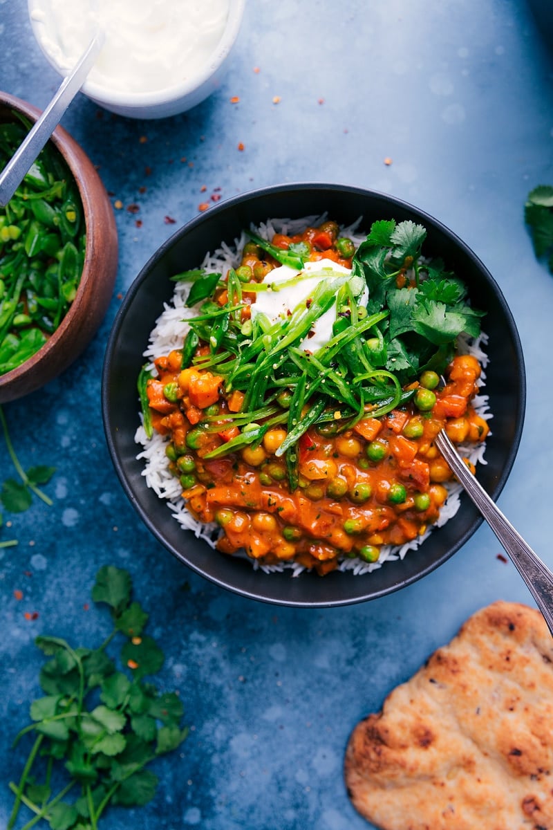Vegetarian tikka masala in bowl with the pea topping, yogurt, and cilantro.