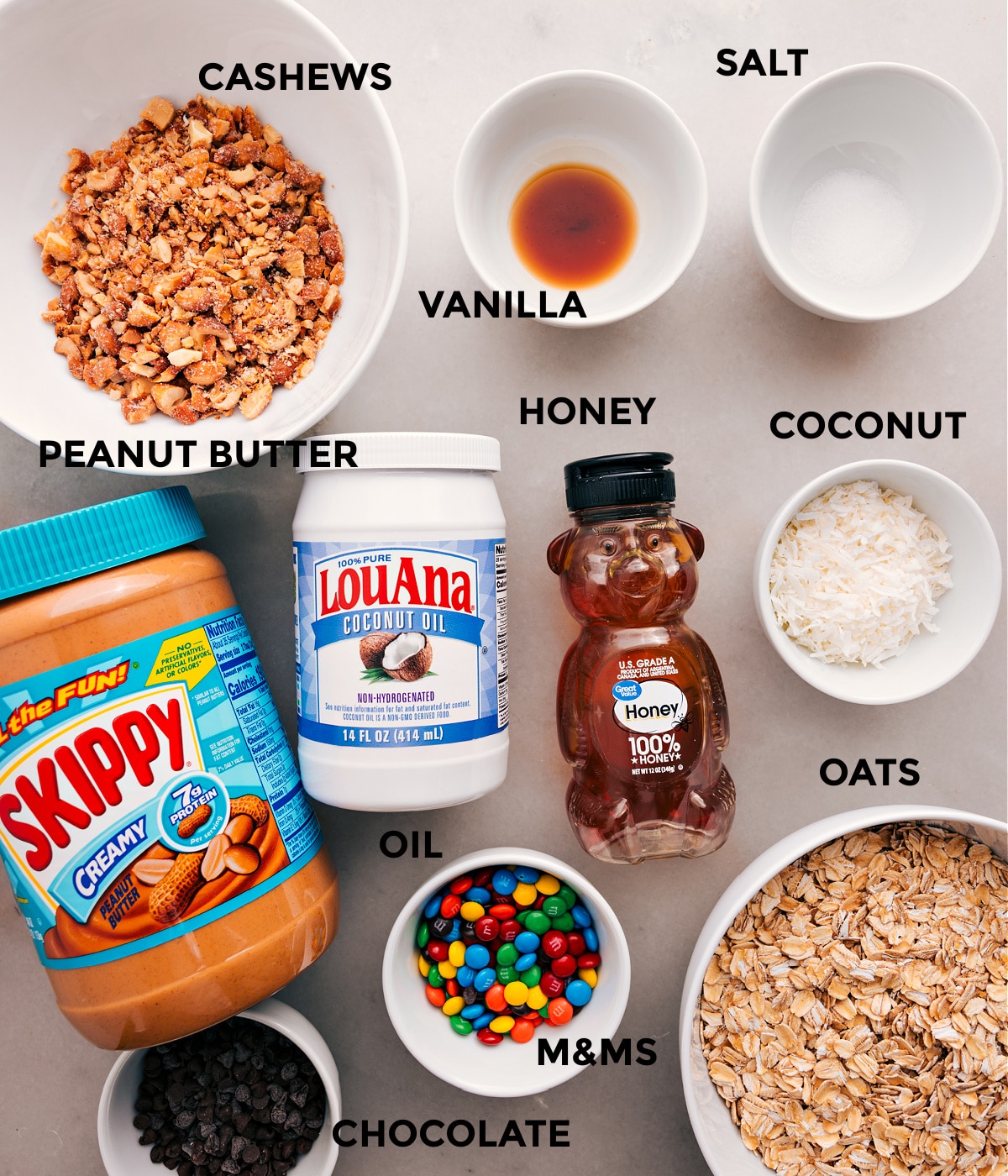 Ingredients In Chewy Granola Bars All the ingredients for this recipe are prepped and ready for easy assembly, including cashews, vanilla, salt, coconut, oats, honey, oil, peanut butter, M&Ms, and chocolate.