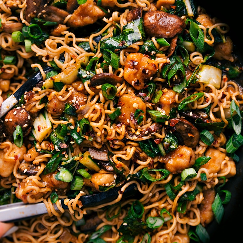 Sweet and spicy General Tso Ramen combines tender chicken, sautรฉed mushrooms, and bok choy with ramen noodles! Recipe via chelseasmessyapron #dinner #quick #easy #simple #best #kidfriendly #mushrooms #veggies #generaltso #ramen Up close overhead image of the General Tso Ramen