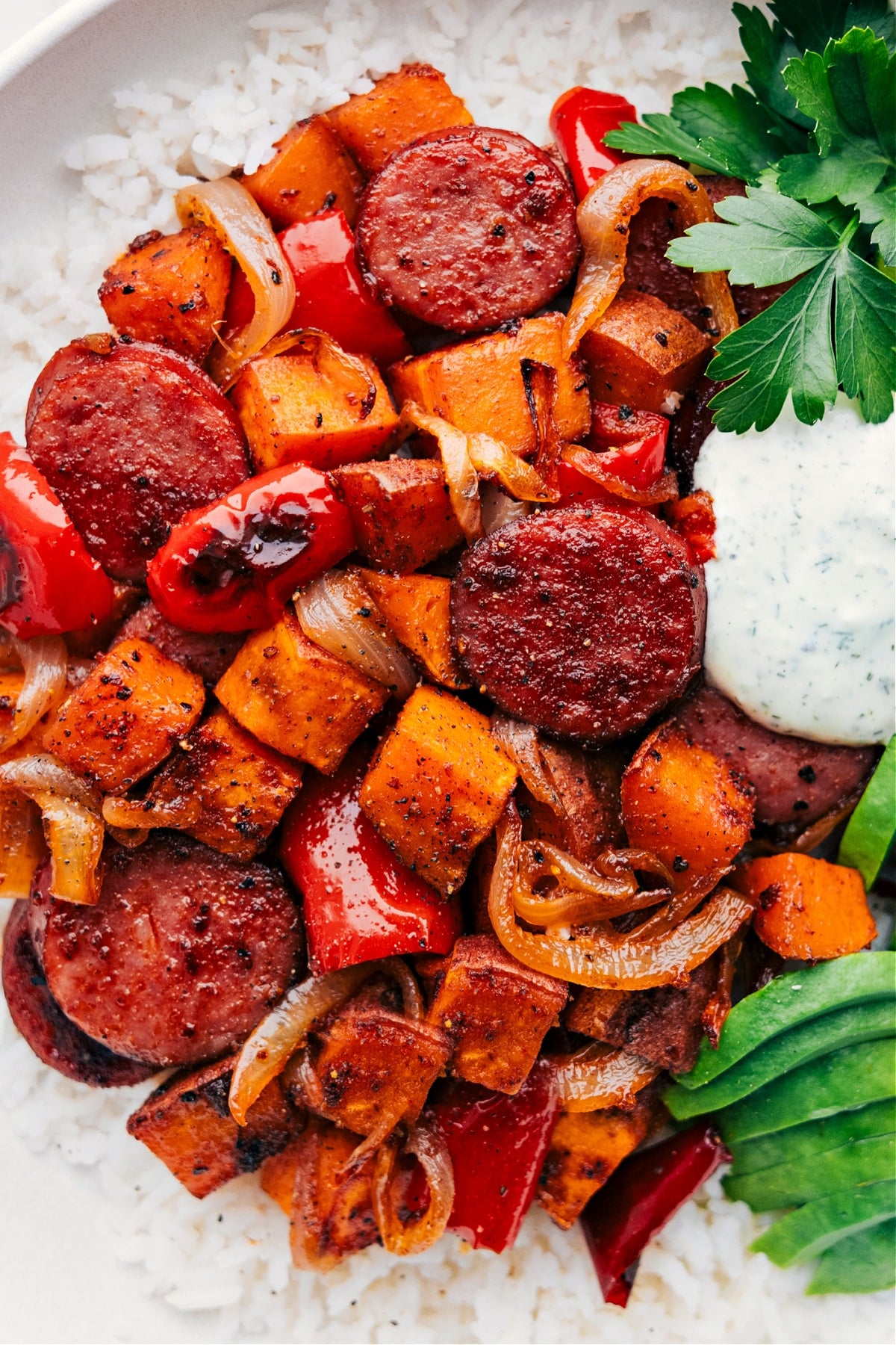 Sweet Potato and Sausage Over Rice - Ready to Serve Hearty dish served over a fluffy bed of rice on a plate, topped with sauce and ready to be enjoyed.