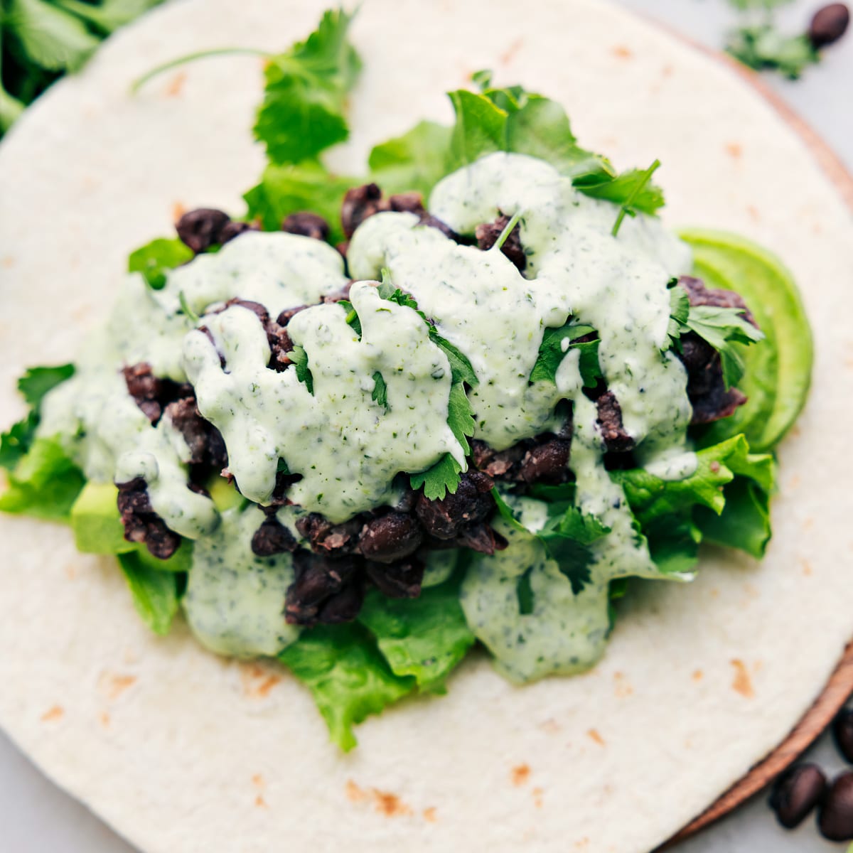 How To Make Black Bean Wraps A black bean wrap, opened up to reveal the delicious filling of avocado, lettuce, black beans, and the most flavorful cilantro lime sauce.