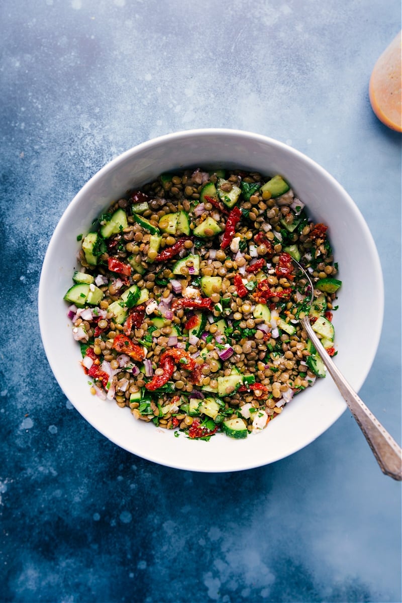 This zippy, fresh Lentil Salad is my latest obsession! With tender lentils, fresh veggies, and the ultimate tangy lemon vinaigrette, you are going to be hooked on this recipe! #side #dinner #protein #healthy #whole #whole30 #clean #cleaneating #cucumber #quick #easy #simple #best #sundriedtomatoes #lentil #salad Lentil Salad in a bowl with bright cucumbers and sun-dried tomatoes.
