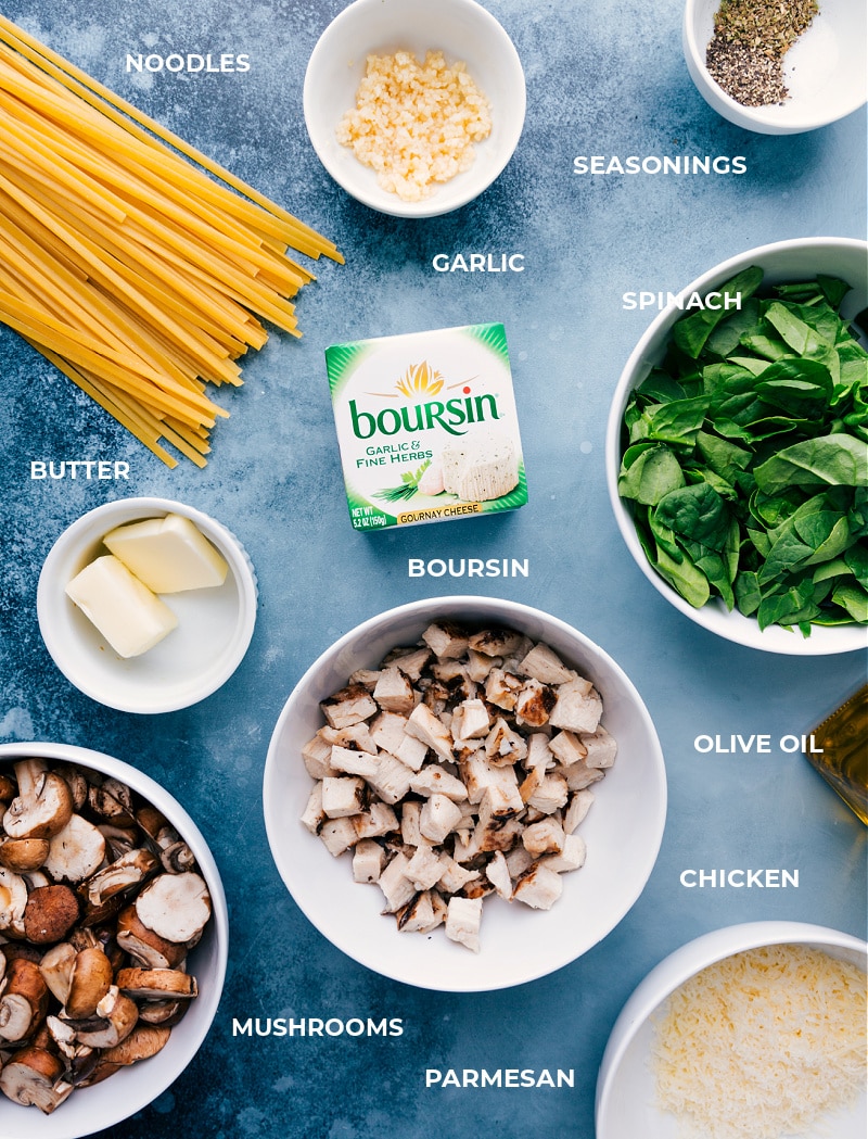 Creamy Chicken Pasta starts with thick noodles cooked to al dente perfection and then tossed with garlic-butter mushrooms, rotisserie chicken, tender spinach, and garlic-herb cheese.ย Recipe via ChelseasMessyApron #dinner #quick #easy #simple #delicious #best #mushrooms #creamy #chicken #pasta All the ingredients for this recipe laid out for easy assemblyโmeat, fettuccine, spinach, seasonings, garlic, olive oil, mushrooms, and Parmesan.