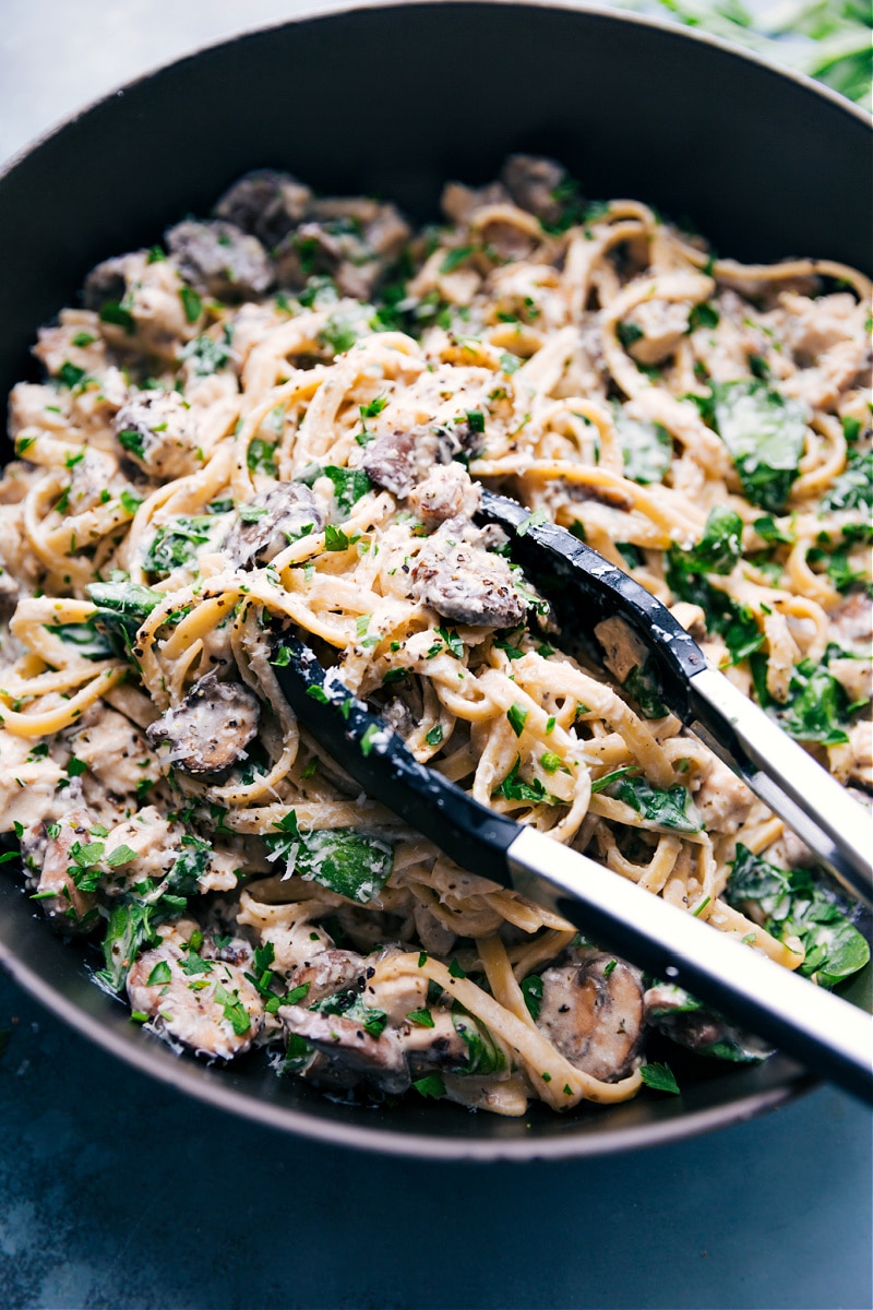 Creamy chicken pasta in a skillet with a big spoonful being lifted out to serve.