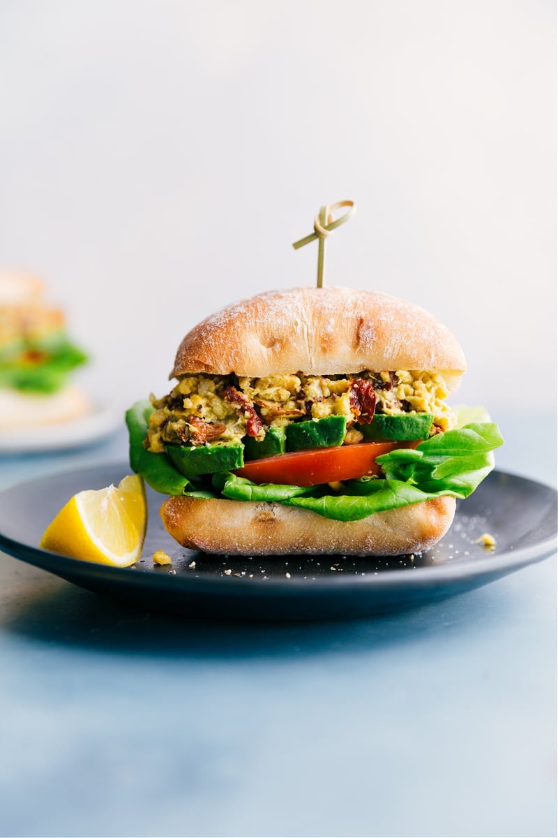 Pesto Chickpea Sandwich Chickpea recipes: pesto chickpea sandwich on ciabatta with tomatoes, avocado, and lettuce inside.