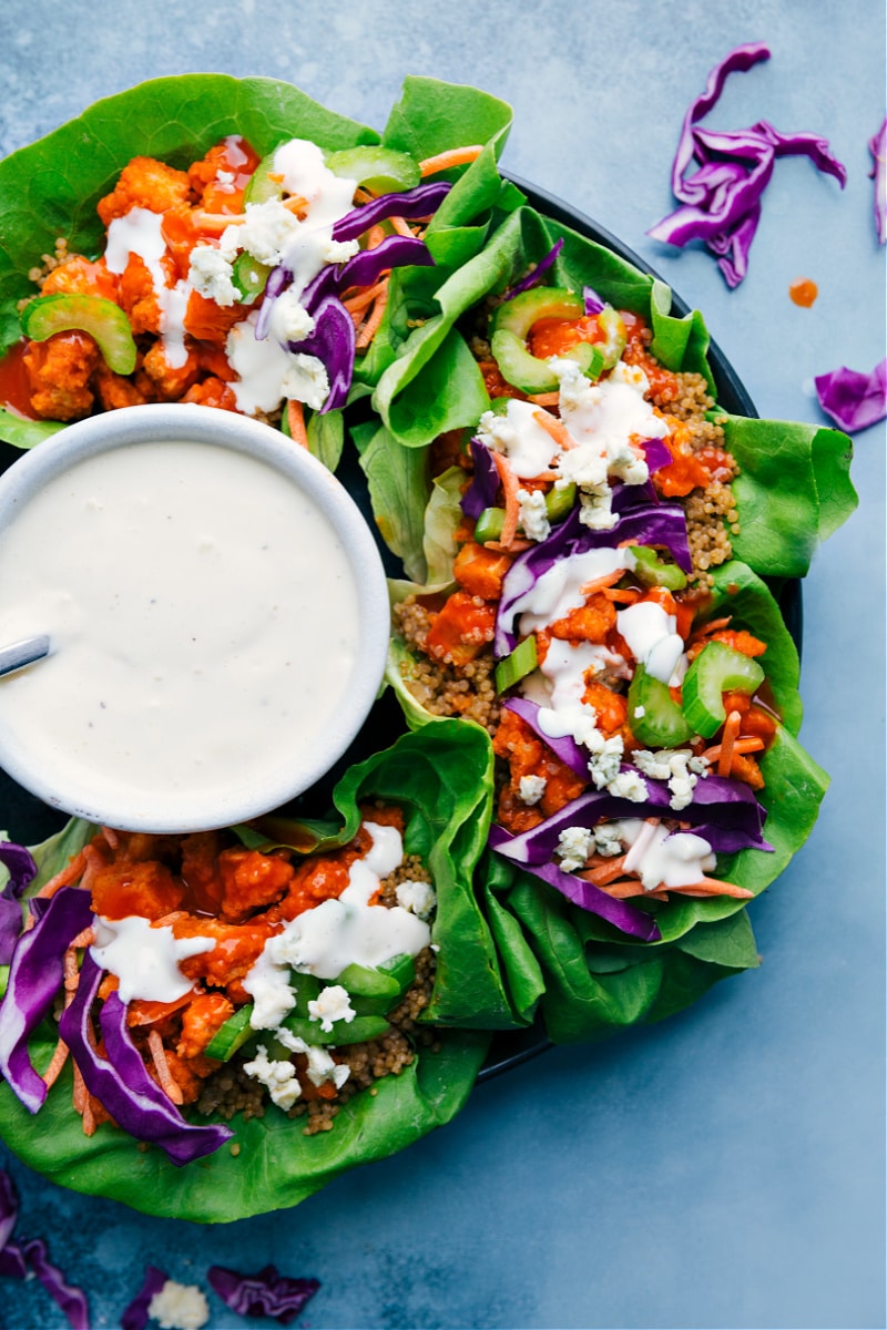Buffalo Chicken Lettuce Wrapsย deliver a good hit of heat with a cooling sauce! Crispy chicken is tossed in zesty buffalo sauce and loaded in crispy lettuce wraps, topped with crunchy veggies, and drizzled in a bold bleu cheese (or ranch!) dressing. Recipe via ChelseasMessyApron #dinner #quick #easy #simple #spicy #sauce #quinoa #buffalo #chicken #lettuce #wraps Overhead image of the Buffalo Chicken Lettuce Wraps