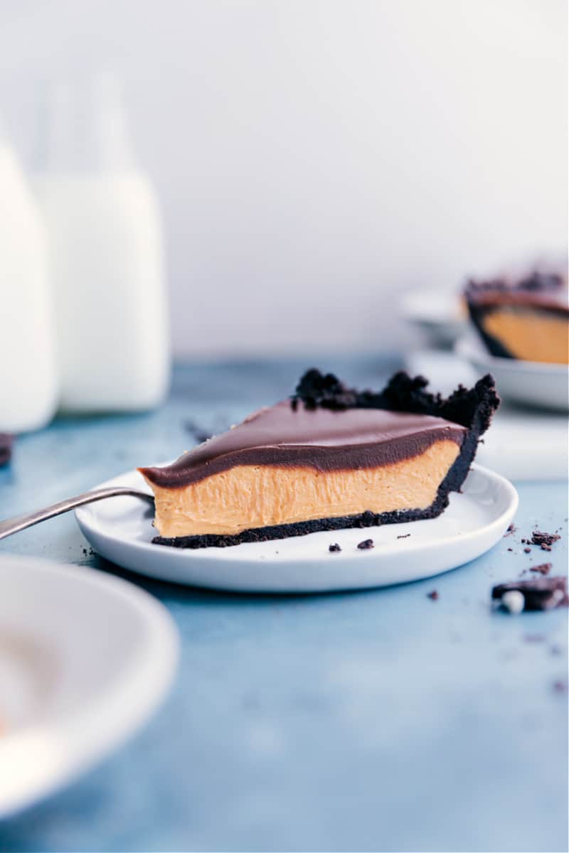 Chocolate Peanut Butter Pie starts with a simple Oreo cookie crust and is filled with a luscious and sweet peanut butter filling. To finish things off, we have a simple chocolate ganache on top -- no baking required for this recipe! Recipe via ChelseasMessyApron #dessert #best #quick #easy #simple #indulgent #chocolate #peanutbutter #pie Chocolate Peanut Butter Pie slice on a plate