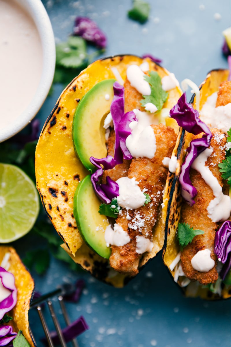 Fish Stick Tacos! Corn tortillas are loaded with a quick slaw, fish sticks (baked or air fried), and an irresistible lime crema. Recipe via ChelseasMessyApron #dinner #quick #easy #simple #best #avocado #cabbage #crema #fishstick #tacos Up-close image of Fish Stick Tacos