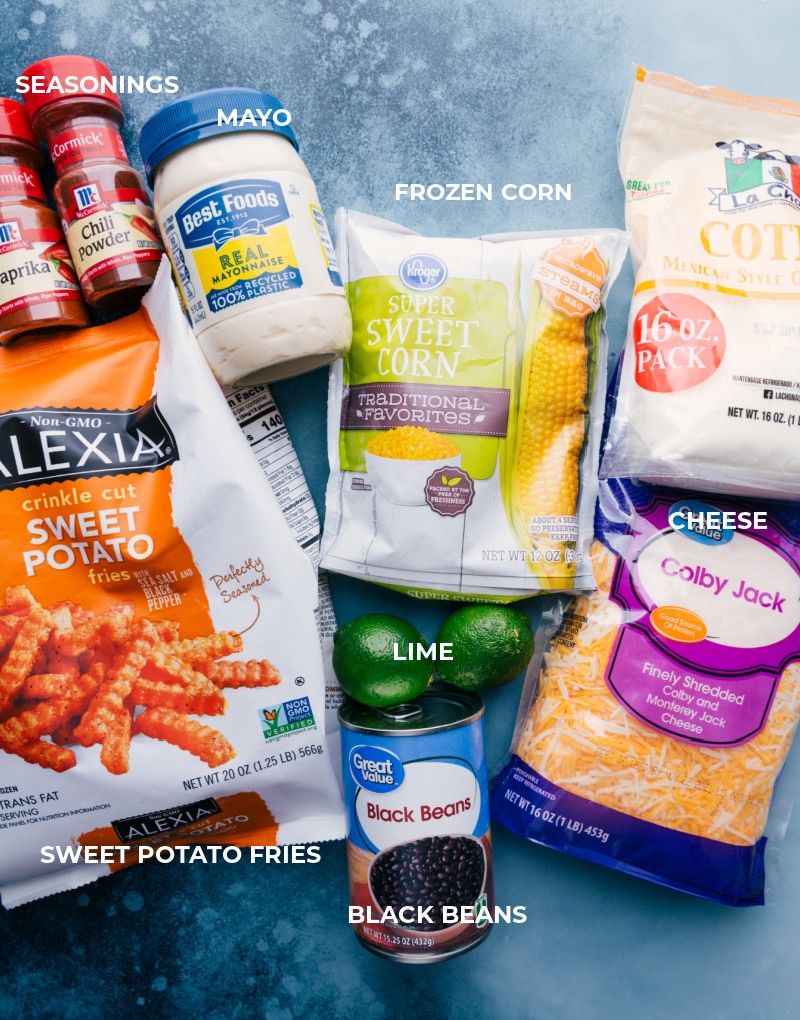 Ingredients In Sweet Potato Nachos All the ingredients in this dish prepped out for easy assembly including seasonings, mayo, sweet potatoes, frozen corn, cotija, black beans, colby jack, and limes.