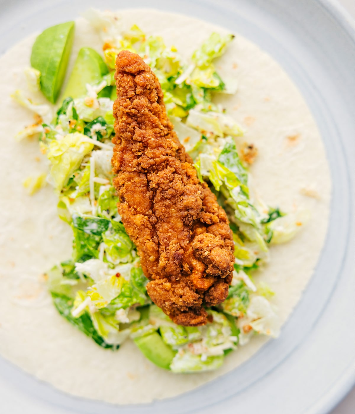 Making Chicken Caesar Wraps For Lunch Piling in all the components of the Chicken Caesar Wrap inside a tortilla.