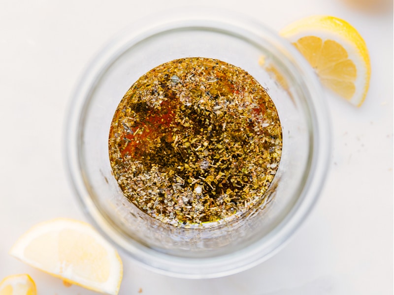 This Greek Salad Dressing is one for the books! This Greek vinaigrette is the perfect accompaniment to so many dishes and simply unbeatable on this easy Greek salad! Recipe via ChelseasMessyApron #best #quick #easy #simple #lemon #greek #salad #dressing Process shots-- images of all the ingredients being added to a jar