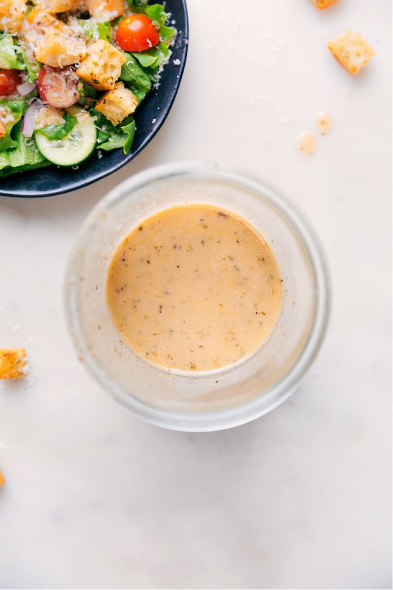 Italian Dressing made from scratch is a complete game changer -- it's so much better than store-bought! This dressing combines olive oil with dried herbs, Dijon mustard, and red wine vinegar for a bright and tangy dressing sure to please a crowd! Recipe via ChelseasMessyApron #quick #easy #simple #healthy #best #vinagrette #italian #dressing Overhead image of the Italian Dressing in a jar