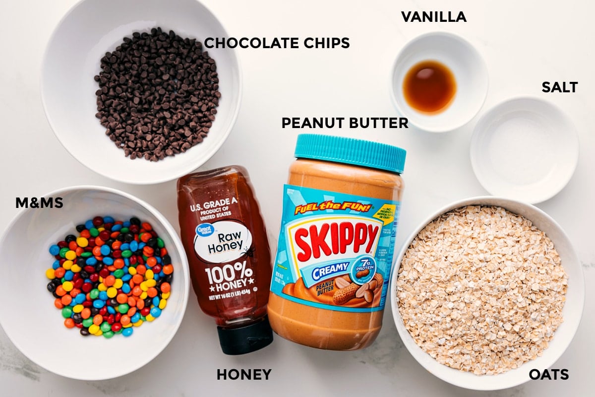 Ingredients In These Monster Energy Balls All the ingredients in this recipe prepped out for easy assembly including m&ms, chocolate chips, honey, peanut butter, vanilla, salt, and oats.