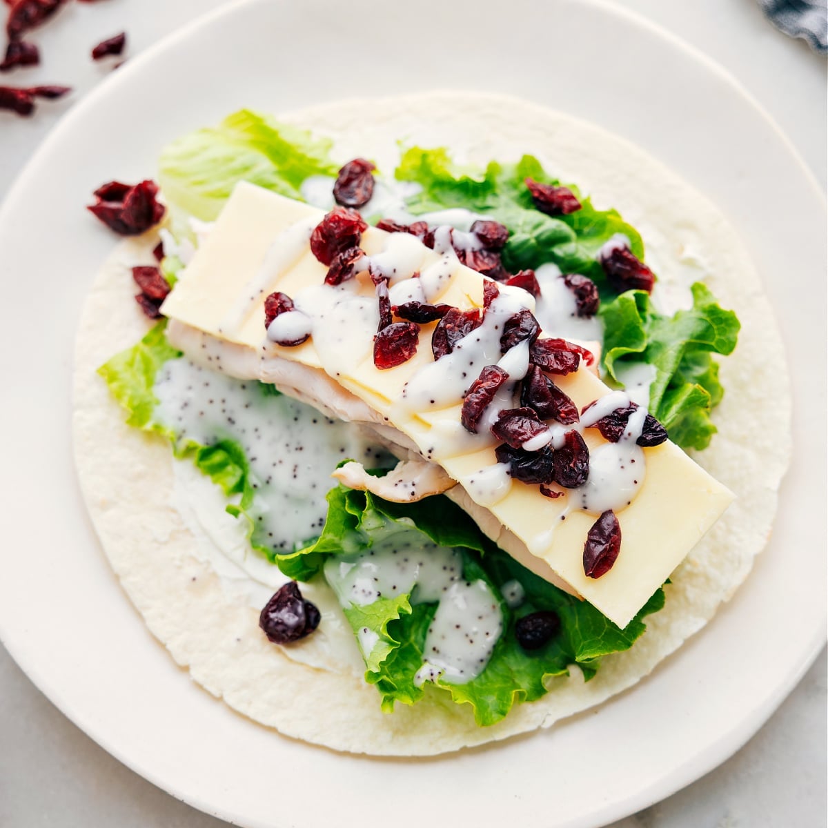 How To Make Turkey Cranberry Wraps All the ingredients assembled on a tortilla.