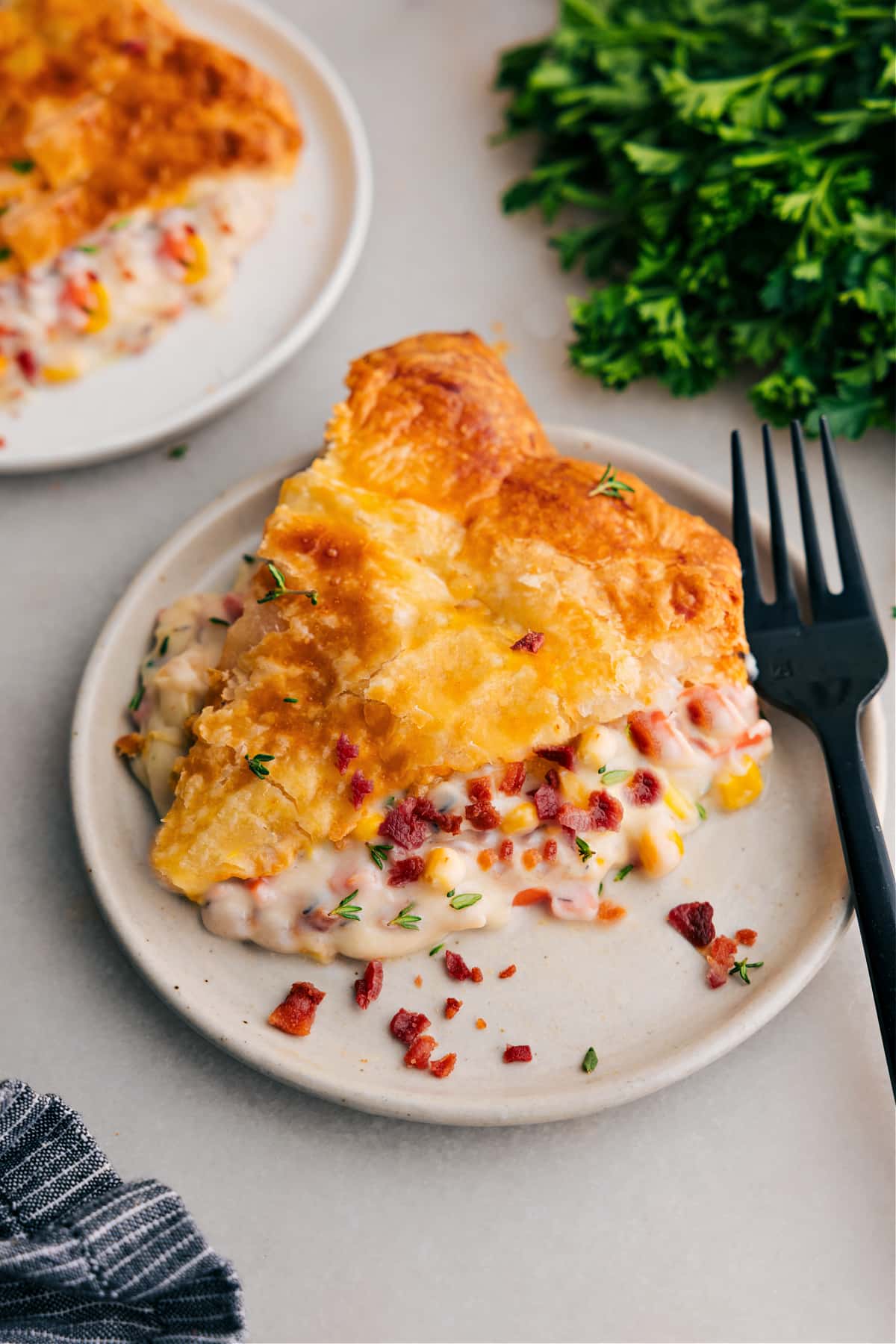 This Corn Chowder Pot Pie channels all the best parts of chicken corn chowder into an ultra-comforting and delicious pot pie! Sweet corn, crisp bacon, and tender chicken in a cheesy sauce all packaged under flaky puff pastry dough -- what more could you want for a comfort-meal type dinner?!ย Recipe via ChelseasMessyApron #dinner #quick #easy #simple #best #comfortfood #familydinner #kidfriendly #corn #chowder #potpie Corn Chowder Pot Pie slice on a plate, ready to enjoy.