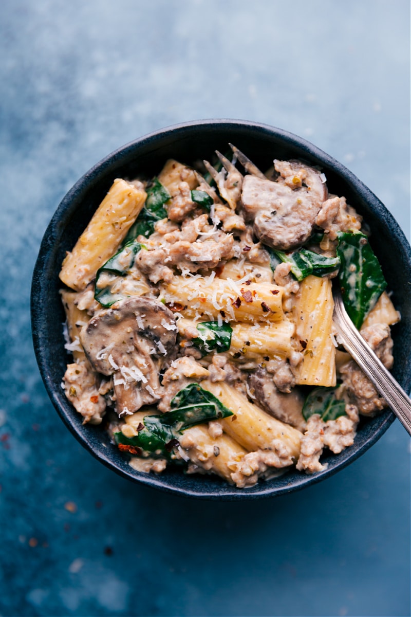 Creamy Sausage And Mushroom Rigatoni is a restaurant-quality meal that is easy to make and is prepared with everyday ingredients. This is comfort food at its finest -- rigatoni pasta tossed in a creamy Italian-seasoned sausage and mushrooms sauce. Recipe via ChelseasMessyApron #dinner #quick #easy #simple #best #comfortfood #kidfriendly #creamy #sausage #mushroom #rigatoni Overhead image of Creamy Sausage and Mushroom Rigatoni