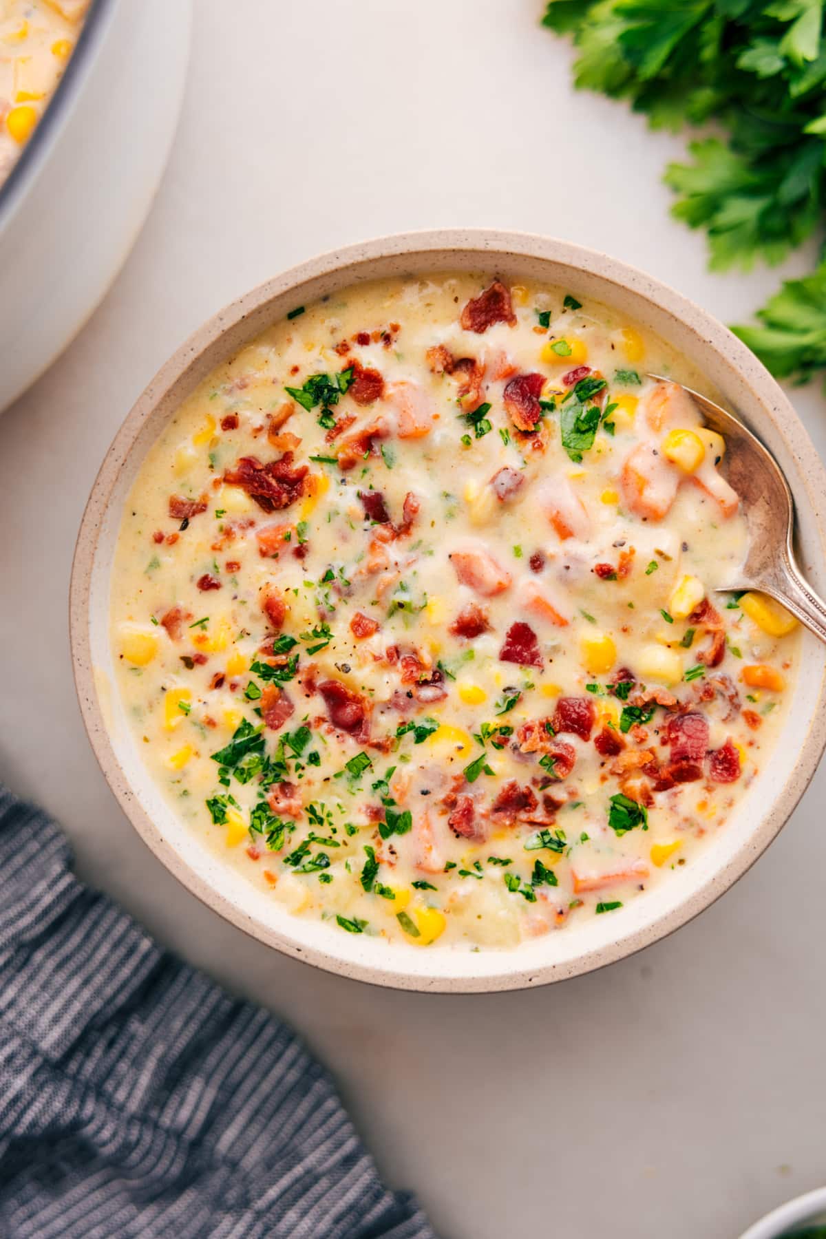 The Best Corn Chowder Recipe Corn chowder topped with crumbled bacon and fresh parsley in a bowl.