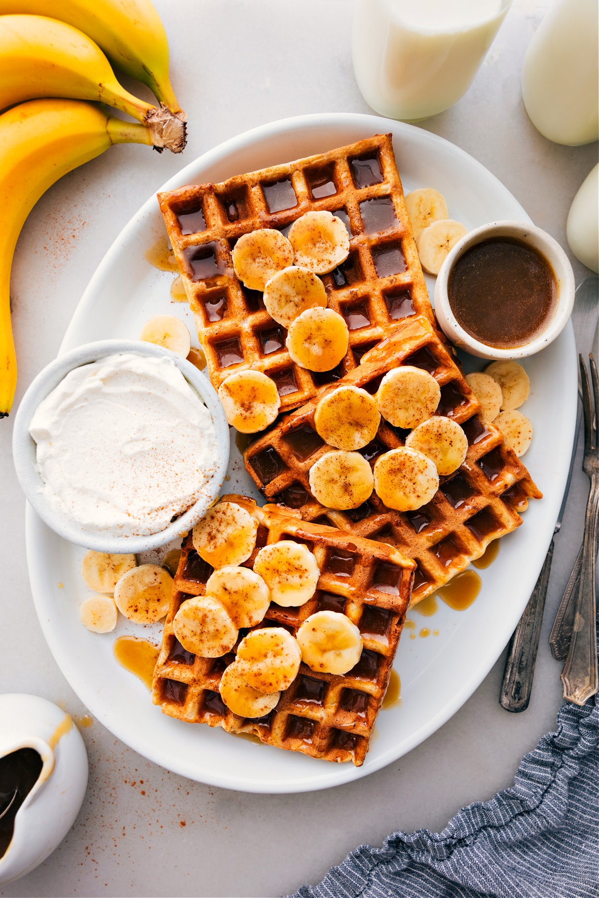 Banana Waffles Recipe Banana Waffles on a platter with syrup drizzled over them.