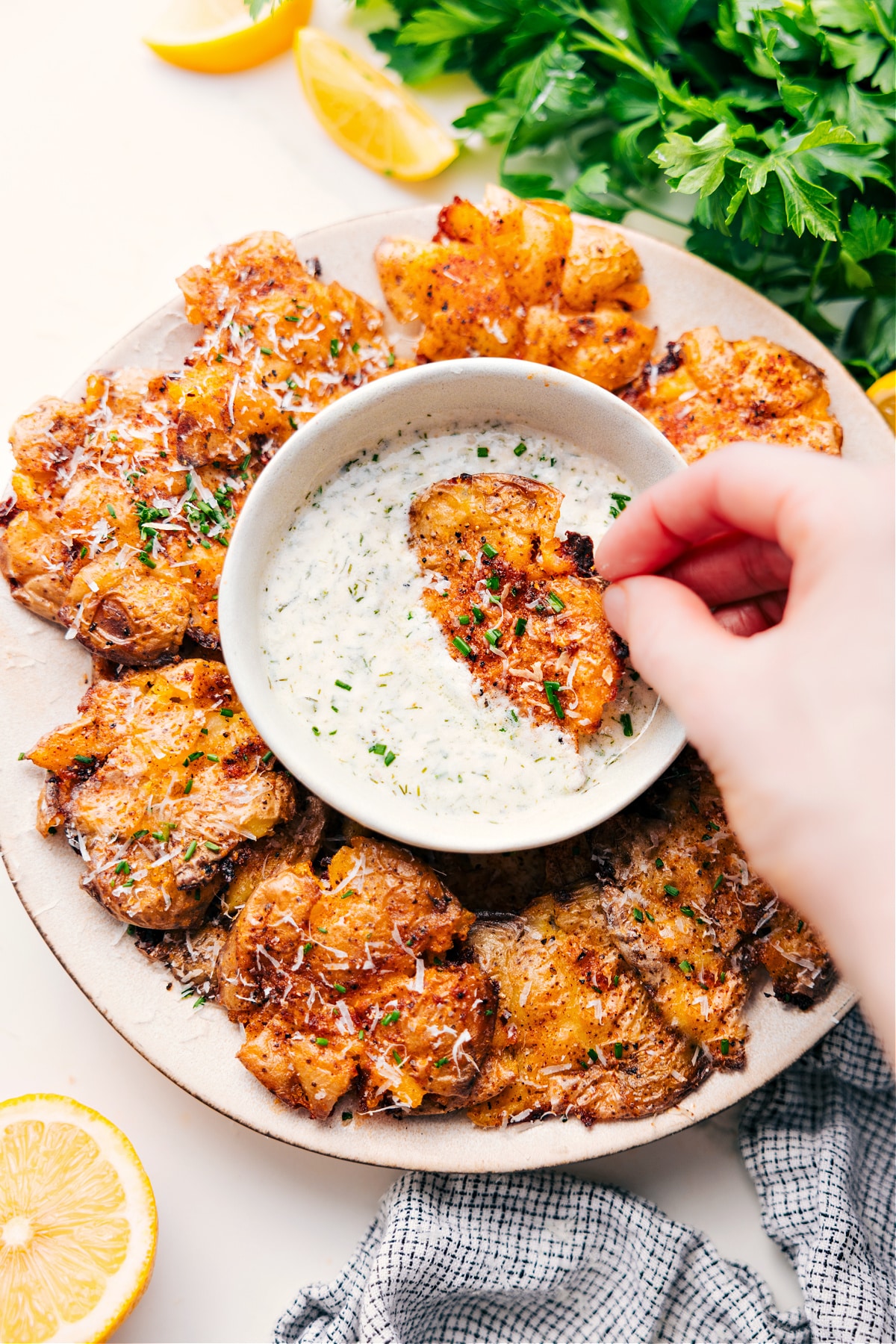 These are our all-time favorite, ridiculously crispy Smashed Potatoes! They're nice and crisp on the outside with light, fluffy interiors and the perfect amount of seasoning and spices! Recipe via ChelseasMessyApron #sidedish #comfortfood #best #quick #easy #thanksgiving #seasonings #parmesan #appetizer #smashed #potatoes Smashed Potatoes Recipe dipping into the homemade lemon dipping sauce.