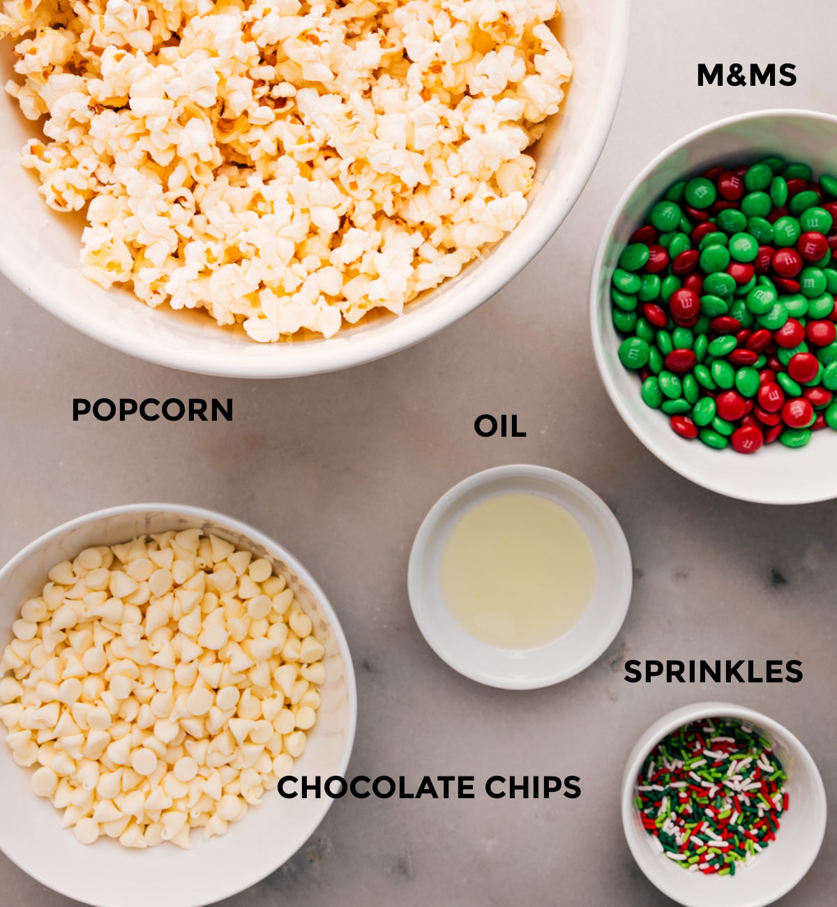 Ingredients In Christmas Popcorn Recipe Prep all the ingredients for easy assembly: M&Ms, oil, sprinkles, popcorn, and white chocolate.