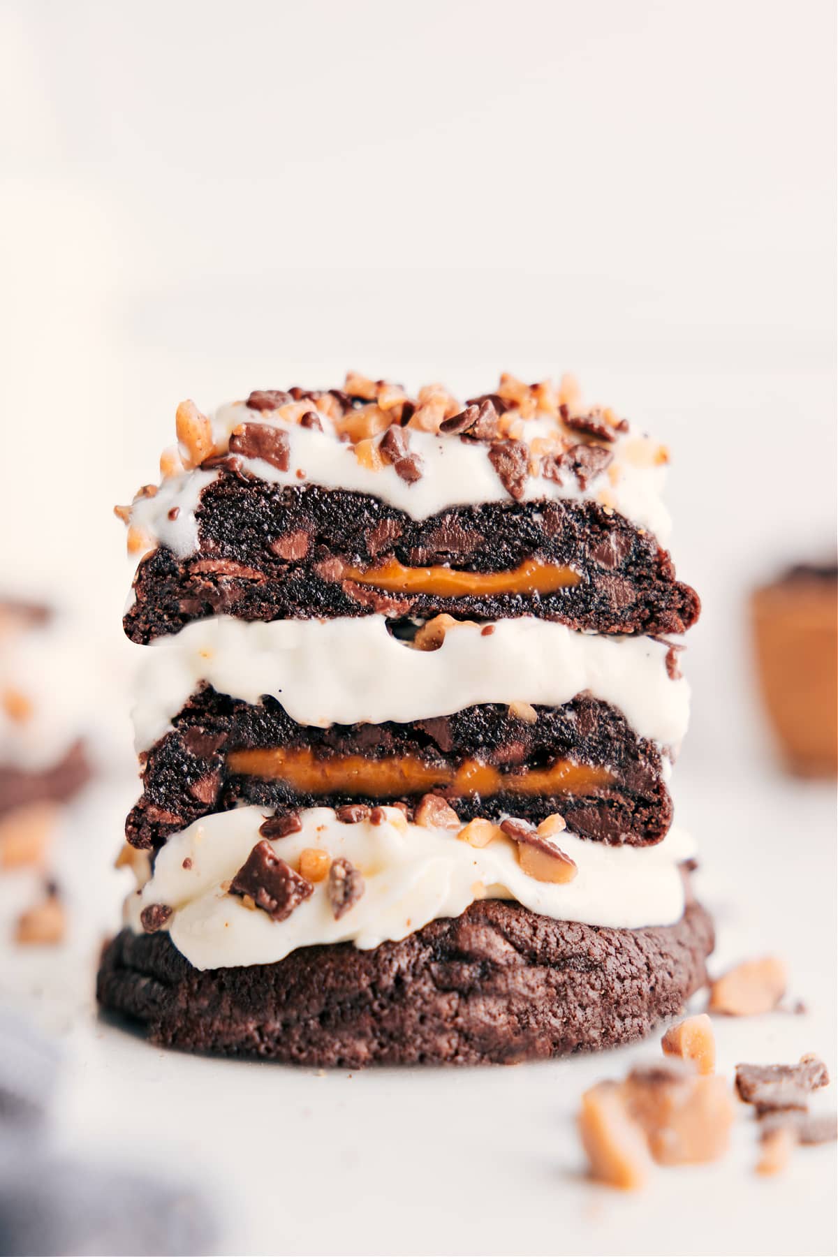 Heath Bar Cookies are a chocolate-lovers dream! Borrowing from the concept of "Better Than Anything" cakes, we're creating the ultimate "Better Than Anything" cookies -- gooey, caramel-loaded chocolate cookies are piled high with whipped cream frosting and garnished with crushed toffee bits. Recipe via ChelseasMessyApron #dessert #best #quick #easy #simple #frosting #candybar #caramel #heathbar #cookies