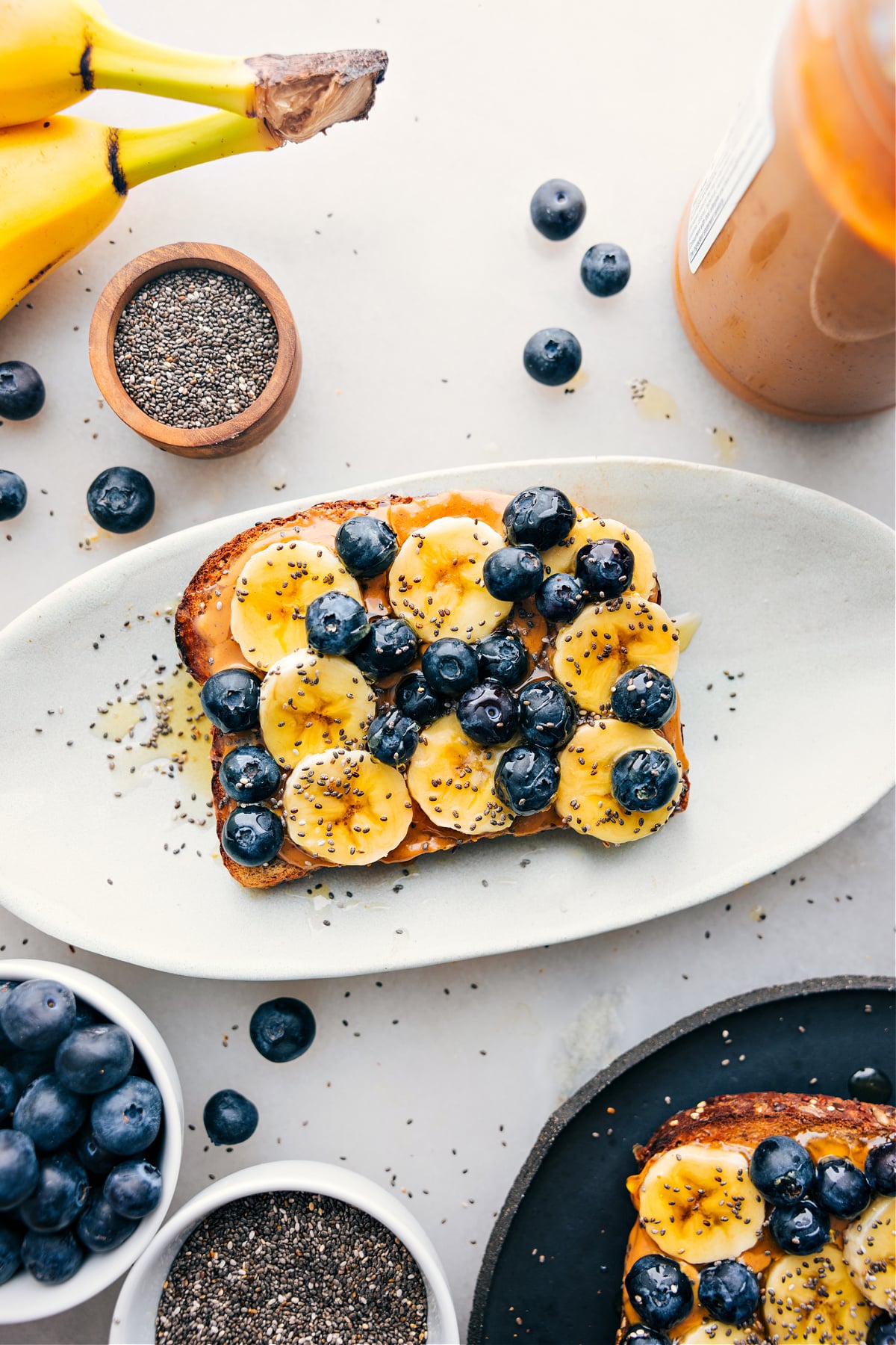 The Best Breakfast Toast Recipe Breakfast toast on a platter with all the fun toppings like bananas, blueberries, chia seeds, and honey.