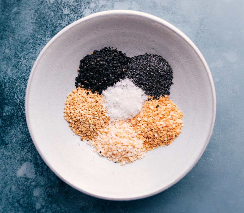 Everything Bagel Seasoning is one of our all-time favorite seasoning blends -- flavorsome, crackly-crunchy, and garlicky! The applications for this seasoning are nearly endless -- obviously you can add it atop homemade bagels, but it also goes great on eggs, avocado toast, or sprinkled into your favorite chicken breading! Recipe via ChelseasMessyApron #garlic #poppyseeds #sesameseeds #everythingbagel #seasoning Overhead image of Everything Bagel Seasoning ingredients all in a bowl