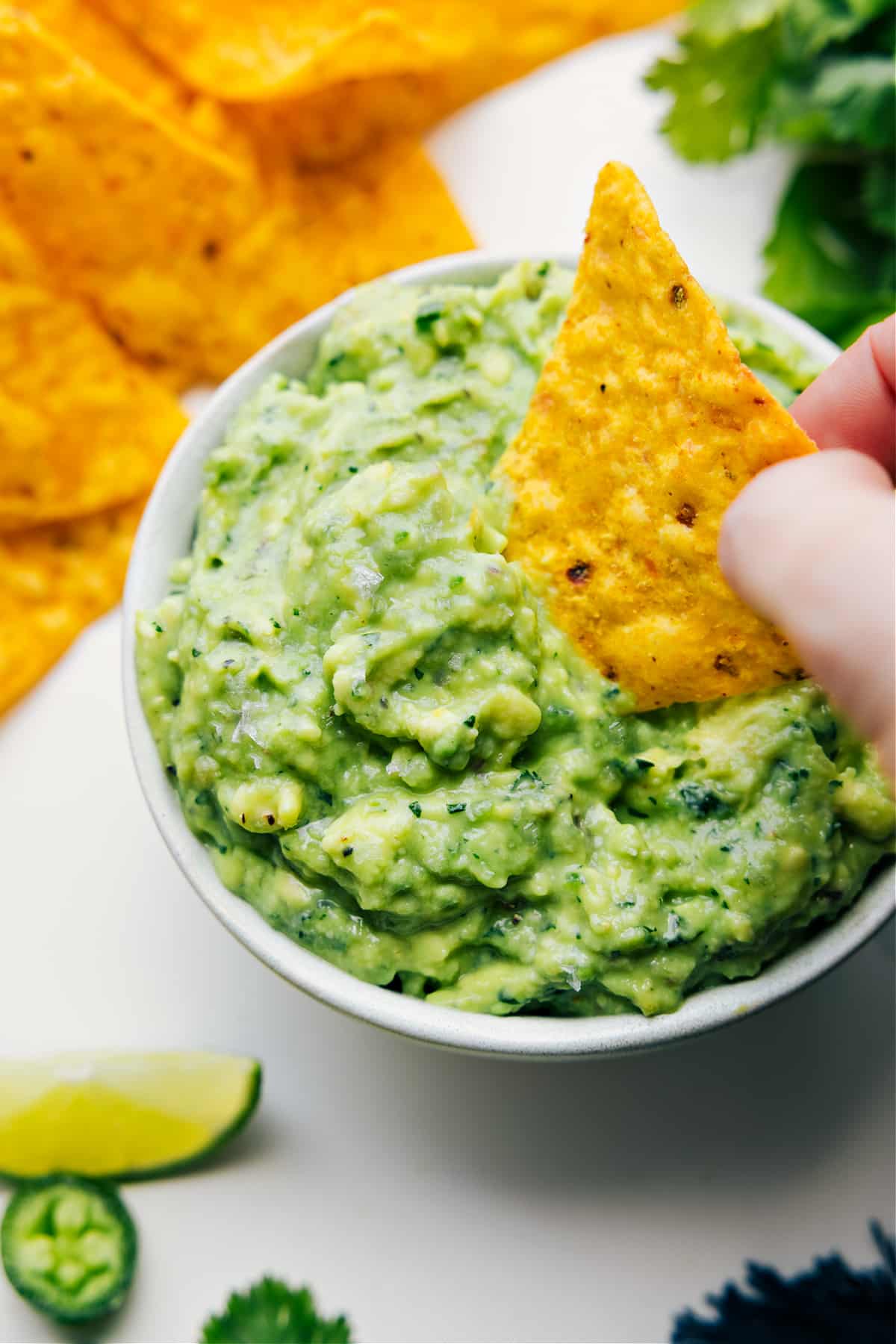 Creamy guacamole recipe in a bowl with a tortilla chip dipped in.