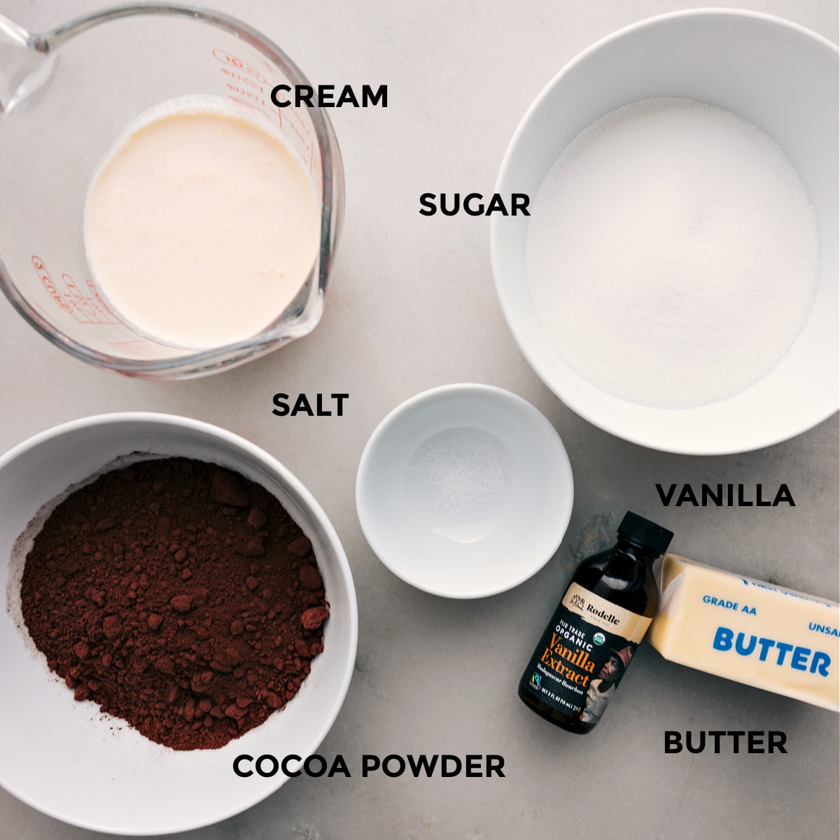 Ingredients In Hot Fudge Sauce This recipe's ingredients are prepped for easy assembly, including sugar, salt, heavy cream, cocoa powder, vanilla, and butter.