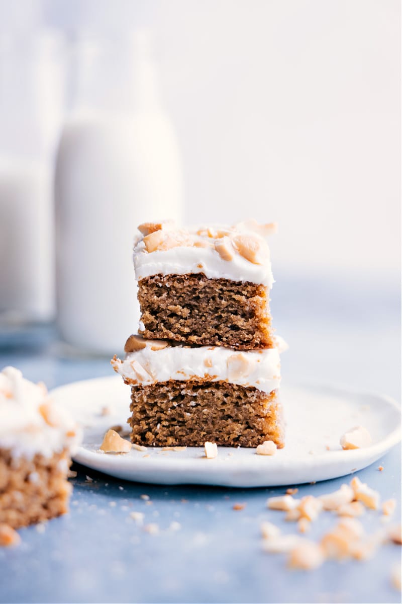 This Cashew Cake is dense, moist, and pairs perfectly with the reduced-fat cream cheese frosting -- yum! Recipe via ChelseasMessyApron #dessert #best #quick #easy #simple #treat #healthy #clean #cleaneating #familyfriendly #kidfriendly #cashew #cake Image of the Cashew Cake slices stacked on top of each other ready to be enjoyed