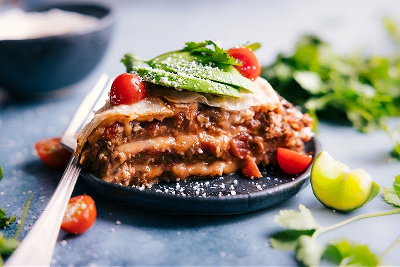 Our favorite Tortilla Pie layers tortillas with creamy refried beans, taco-seasoned beef, saucy salsa, and plenty of melty cheese. Layer this pie like a lasagna, bake it, and add all your favorite taco toppings! Recipe via ChelseasMessyApron #dinner #quick #easy #simple #best #familyfriendly #kidfriendly #tortilla #pie Image of the Tortilla Pie on a plate, ready to be served