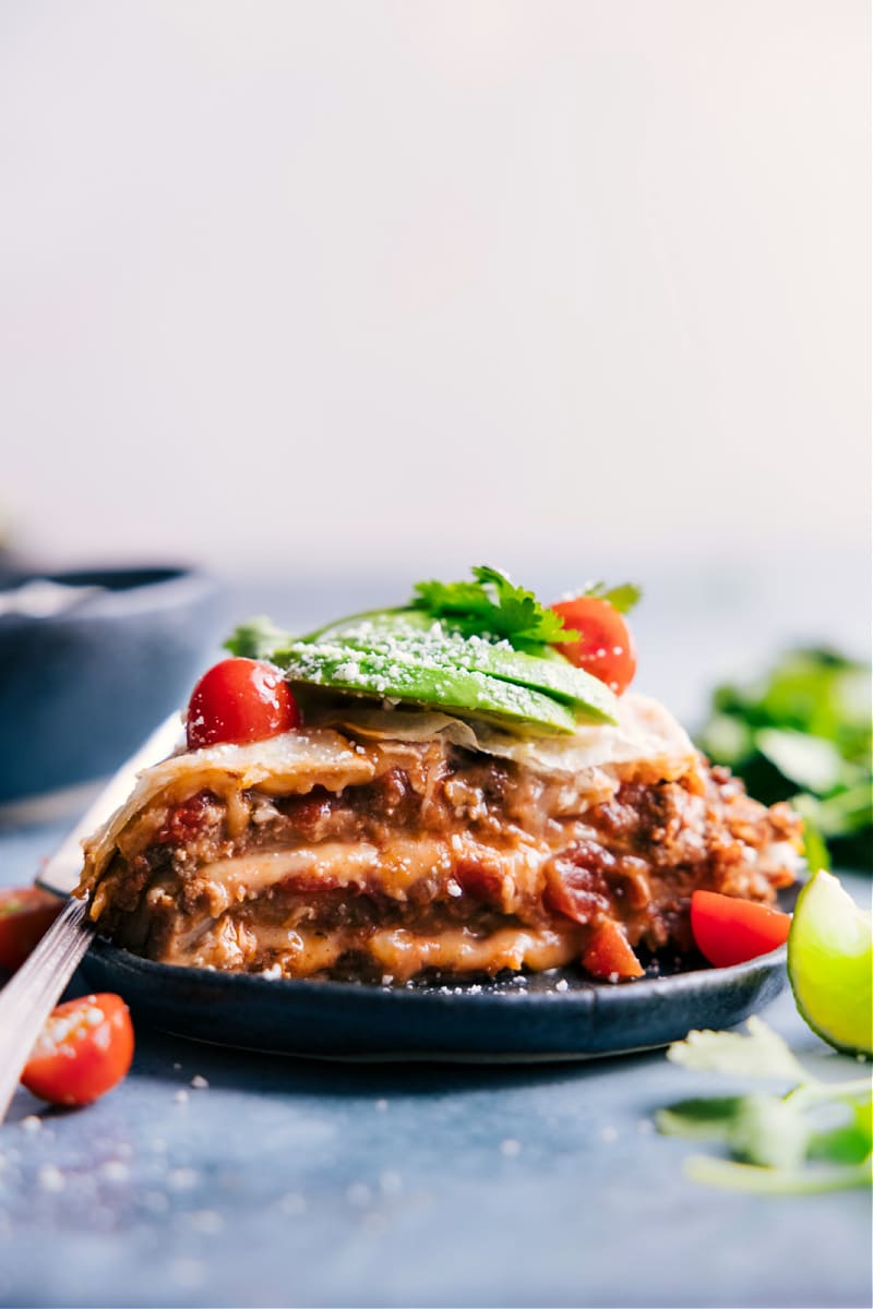 This simple Tortilla Pie layers tortillas with creamy refried beans, taco-seasoned beef, saucy salsa, and plenty of melty cheese. Layer this pie like a lasagna, bake it, and add all your favorite taco toppings! Recipe via ChelseasMessyApron #dinner #quick #easy #simple #best #familyfriendly #kidfriendly #tortilla #pie Image of Tortilla Pie on a plate