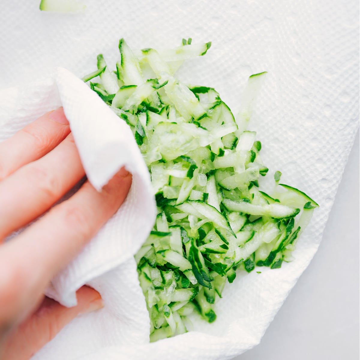 How To Make Tzatziki Sauce Pressing out extra liquid from the cucumber to keep the sauce thick.