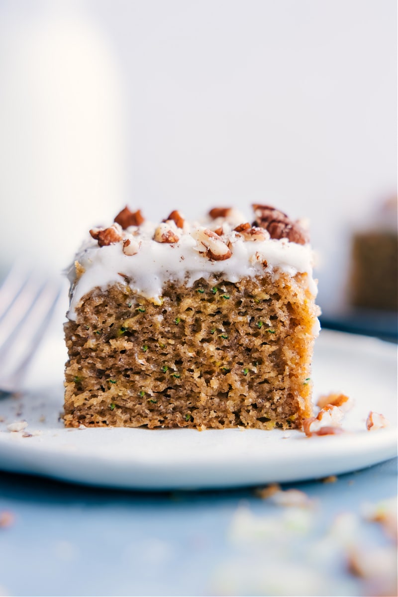 A super flavorful and perfectly moist Zucchini Cake complete with a dreamy cream cheese frosting. And no one will be the wiser that this cake is actually made without any flour, refined sugars, or dairy -- yes, really! Recipe via ChelseasMessyApron #dessert #best #quick #easy #simple #treat #cleaneating #nosugar #toddlertreats #kidfriendly #familyfriendly #zucchini #cake Image of the Zucchini Cake on a plate