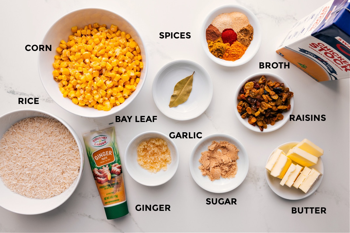 Ingredients In Yellow Rice Recipe All the ingredients in this recipe prepped out for easy assembly including the rice, corn, ginger, bay leaf, garlic, sugar, butter, raisins, broth, and spices.
