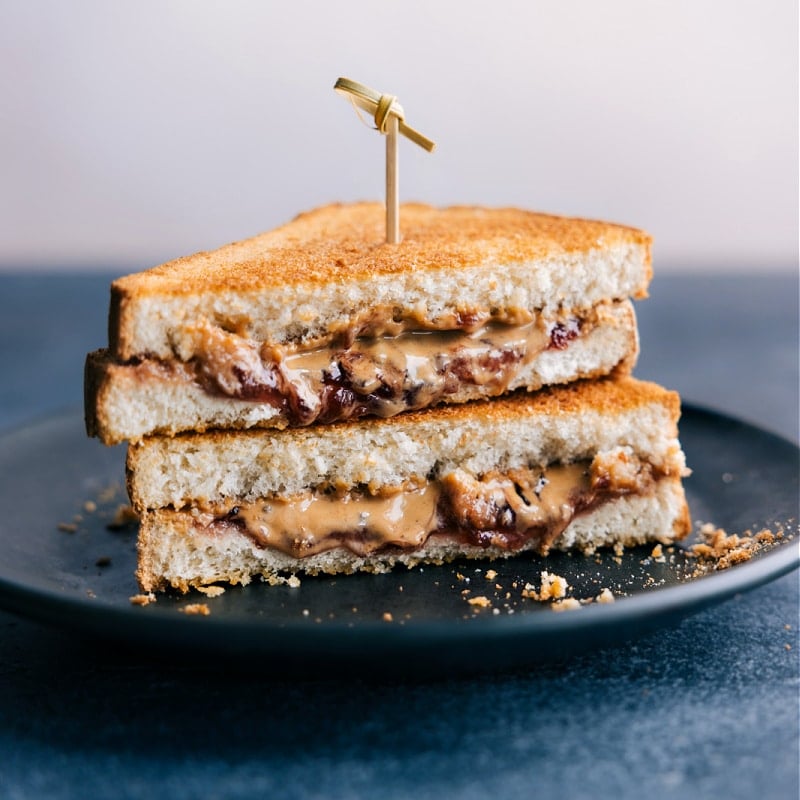 Does anything beat a good peanut butter and jelly? Yes -- an air-fried peanut butter and jelly! Today we're sharing an Air Fryer Sandwich recipe 4 different ways! These sandwiches are perfect for a meal on the go, quick lunch or snack, or light dinner! Recipe via chelseasmessyarpon.com #dessert #quick #easy #simple #best #afterschoolsnack #airfryer #sandwich Image of the Air Fryer Sandwich on a plate, ready to be enjoyed