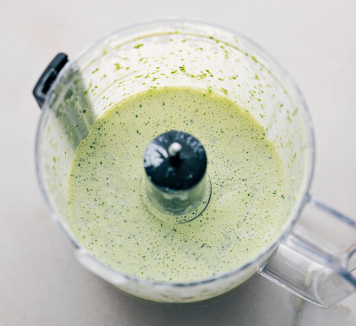 The Best Cilantro Lime Sauce Recipe All the ingredients being pulsed together in a food processor.