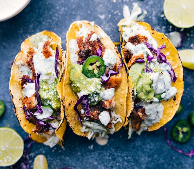 These tasty Tilapia Fish Tacos are the best! These tacos are light, flavorful, and packed with good-for-you ingredients! Recipe via ChelseasMessyApron #dinner #quick #easy #simple #best #fresh #clean #cleaneating #familyfriendly #kidfriendly #tilapia #fish #tacos Image of three Tilapia Fish Tacos, ready to be enjoyed