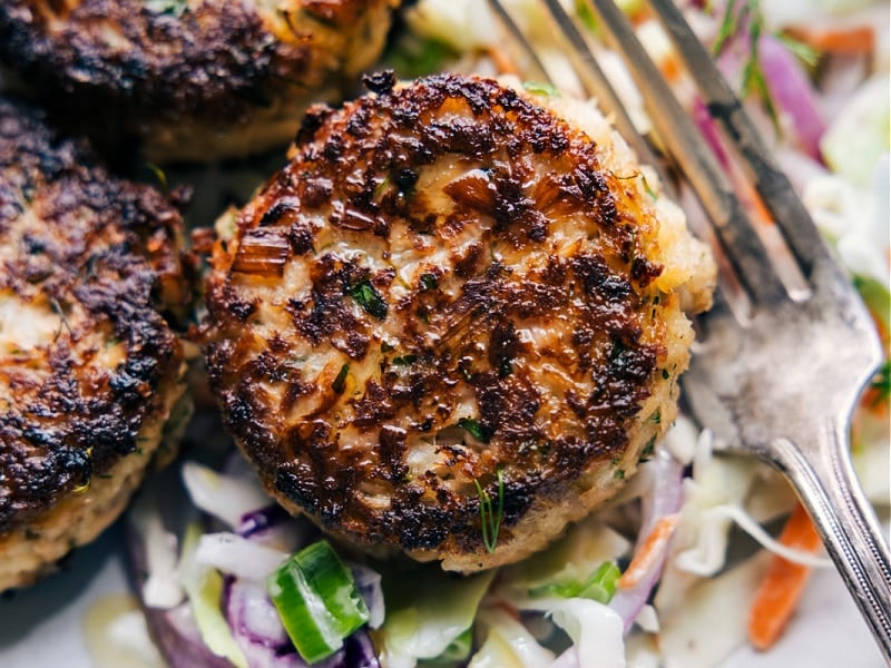 The best Tuna Patties are packed with flavor and have the best texture -- crisp on the top and bottom with a soft (never dry or hard) interior. These patties are so quick and easy to make (thank you canned tuna!) and sure to be a family favorite! Serve your patties over a quick (2-ingredient) slaw and with a tasty tartar sauce. Recipe via ChelseasMessyApron #dinner #quick #easy #simple #best #fresh #familyfriendly #kidfriendly #tuna #patties Up close image of Tuna Patties